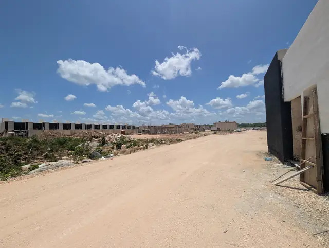Calle amplia del residencial Jardines del Sur 7 con las manzanas en construcción al fondo, Cancún